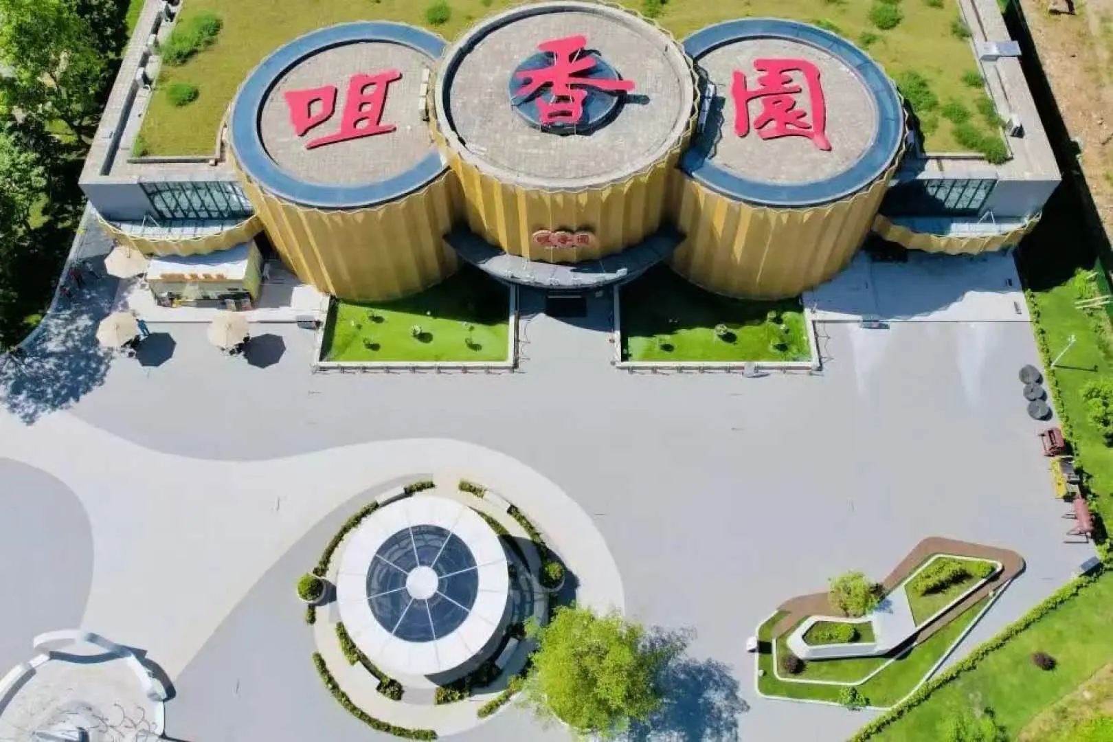 中山【咀香園餅文化博物館】鳥瞰圖，展示其獨特的圓筒形建築和周圍綠化景觀，是短線團參觀的文化景點。