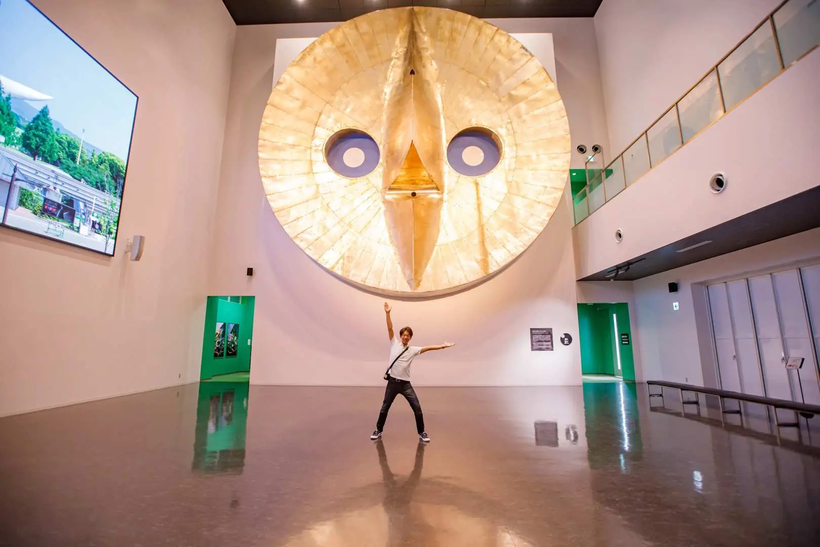 太阳之塔内部独特展区，游客在巨大的金色面孔雕塑前张开双臂，亲身感受冈本太郎为大阪万博创造的艺术震撼。