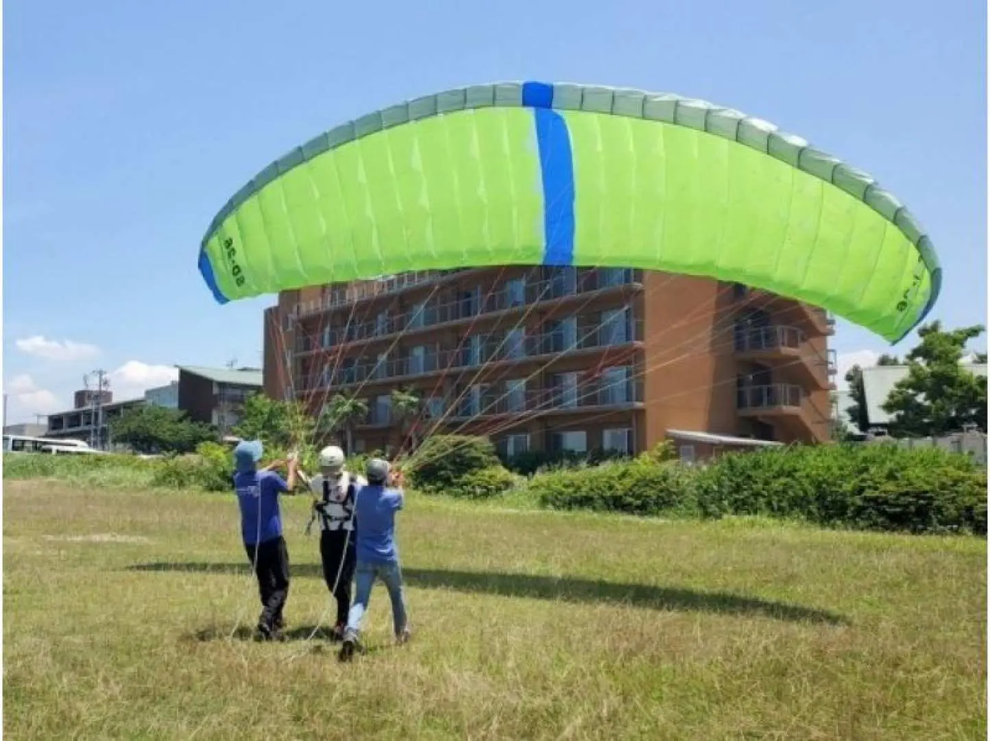 Ground training begins. The paraglider is filled with wind, and the pilots practice controlling it on the ground.