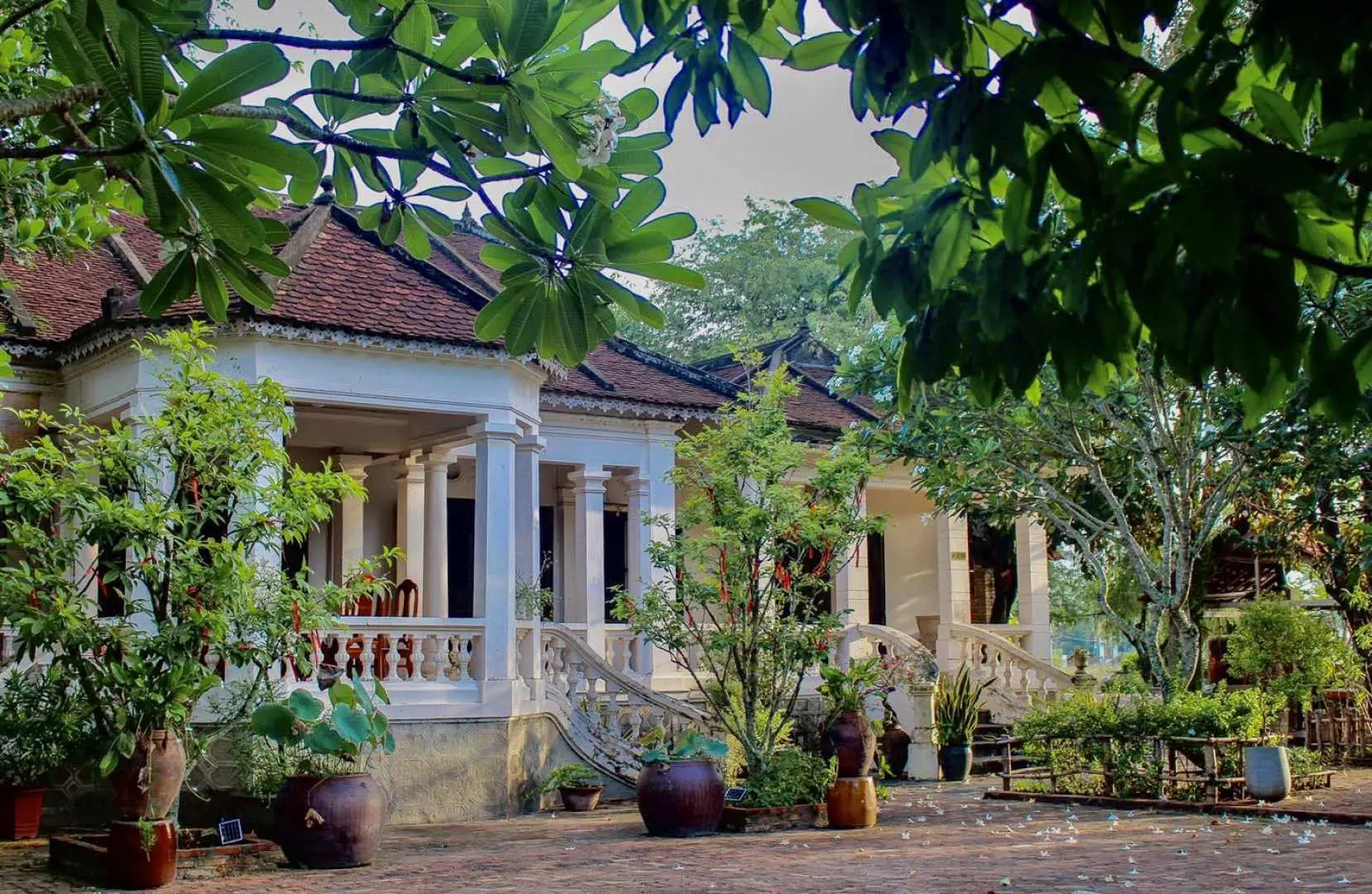 บ้าน Memento Country Home อันสง่างาม อาคารสไตล์โคโลเนียลที่มีเสน่ห์ด้วยเสาสีขาวและหลังคากระเบื้องสีแดง ตั้งอยู่ในสวนเขียวชอุ่มในชนบทของญาจาง.
