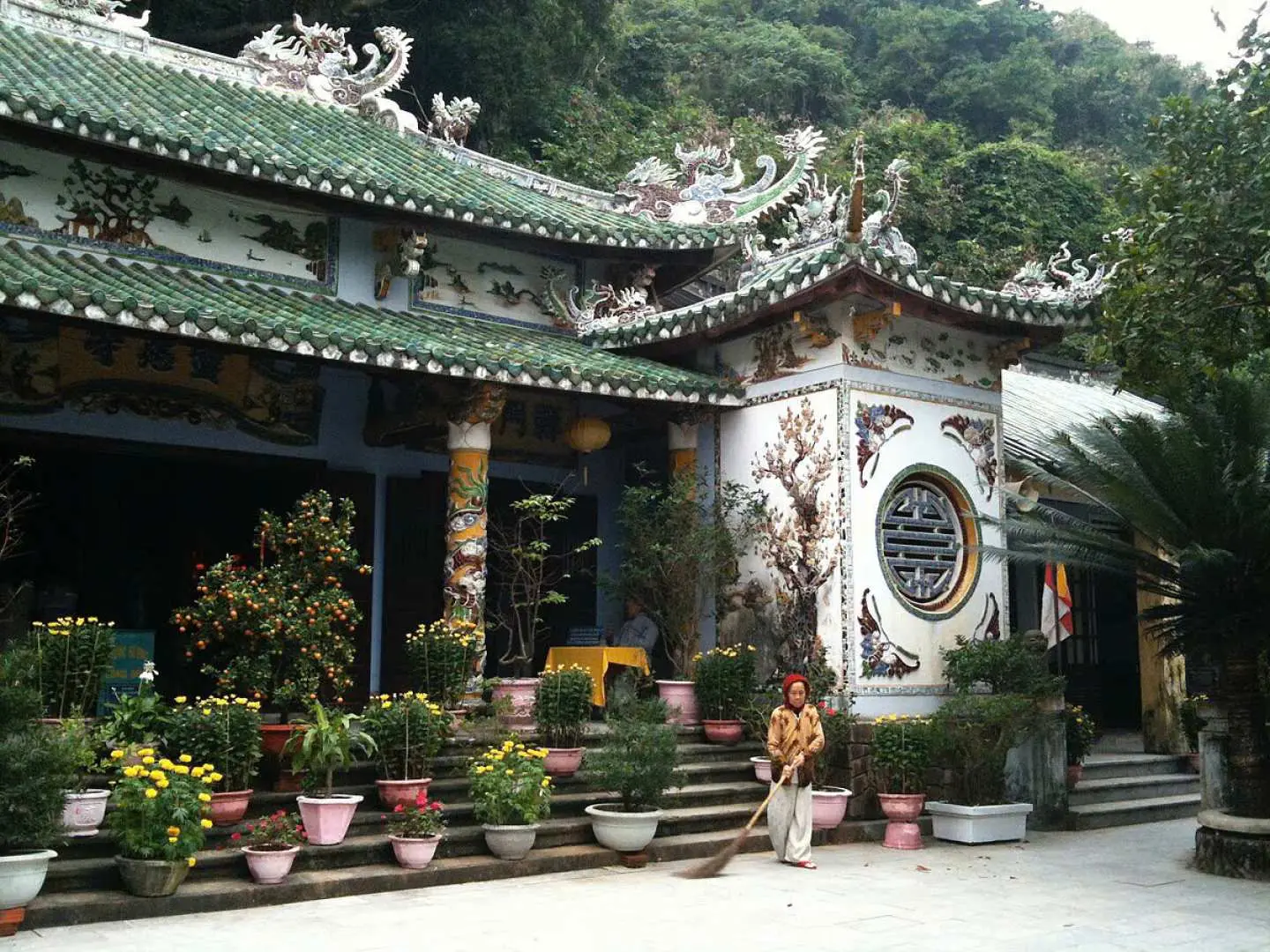 五行山一座寧靜的古老寶塔，採用傳統越南建築風格，屋頂飾有華麗的綠色瓦片，周圍環繞著鬱鬱蔥蔥的盆栽植物和樹木。