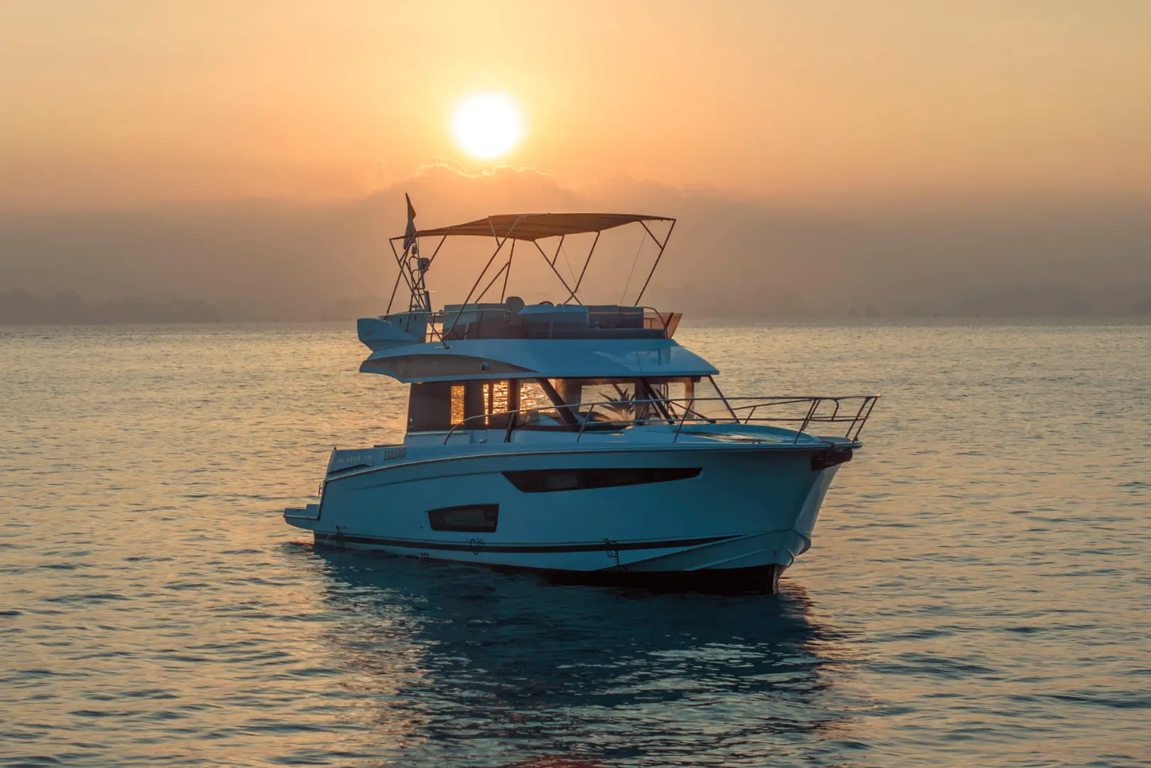 A private yacht cruises through the golden hues of a Halong Bay sunset, creating a serene and romantic atmosphere perfect for couples and private groups.