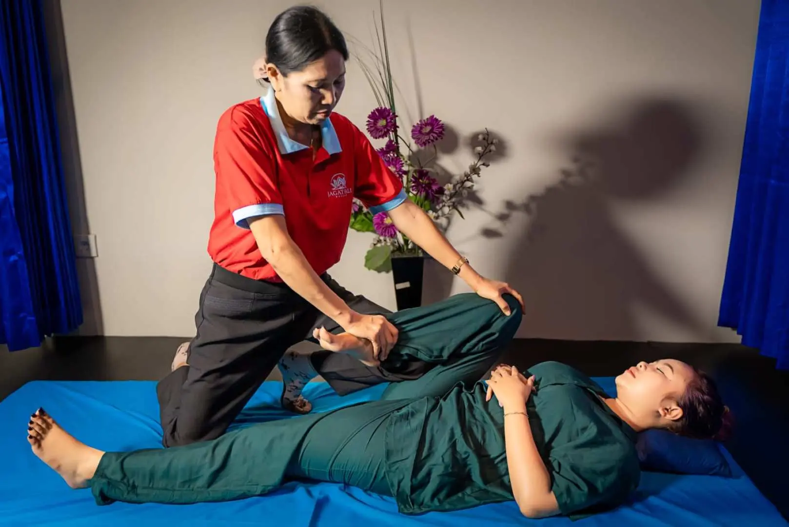 巴厘岛 Jagat Bali Massage 技师正为顾客进行腿部按摩与伸展，运用专业手法帮助舒缓腿部疲劳。