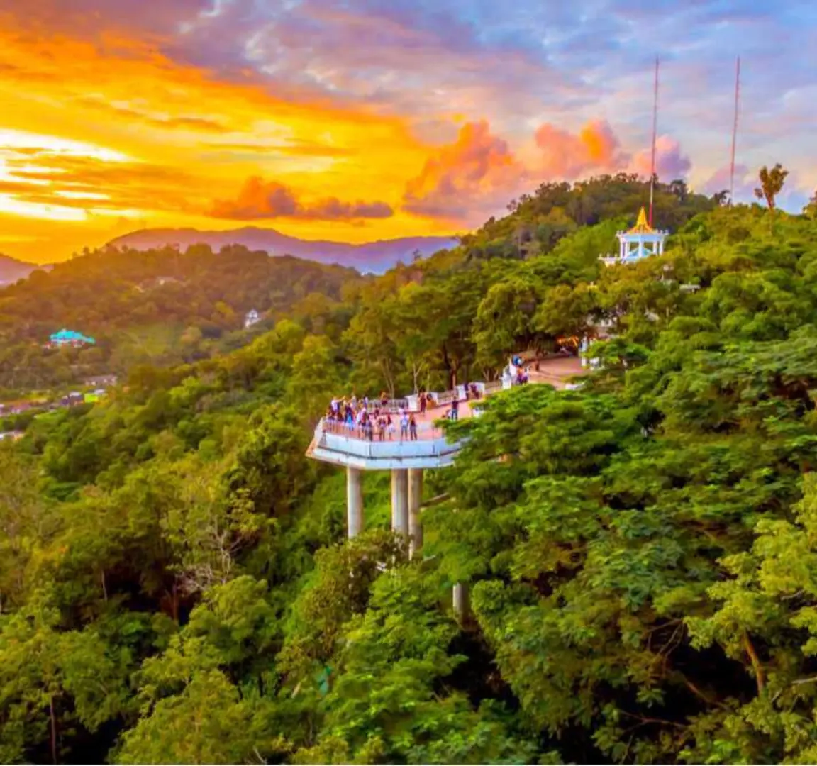 普吉島熱門觀景台的鳥瞰圖，遊客們在夕陽餘暉下，俯瞰鬱鬱蔥蔥的群山與遠方島嶼，盡享壯麗全景。