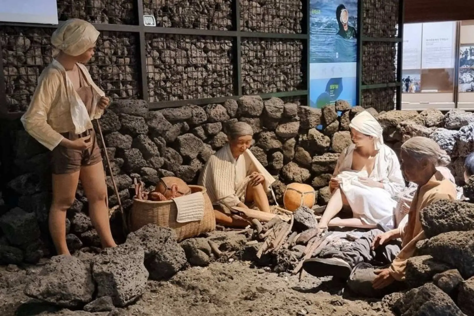 濟州島東部海女博物館展示，多個海女模型圍繞著火堆，呈現昔日海女們休憩與交流的日常。