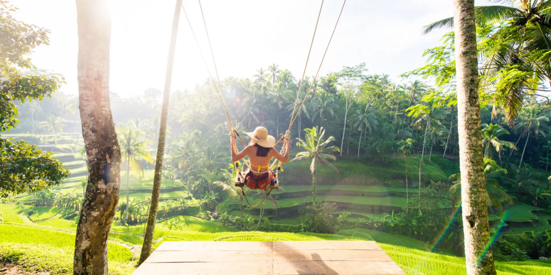 A traveler joyfully soaring on a famous Bali swing high above the vibrant Tegalalang Rice Terraces, capturing iconic Instagrammable views and thrilling experiences.