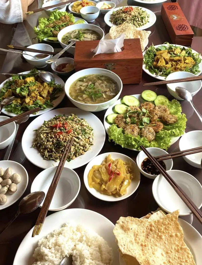 A bountiful Vietnamese family-style lunch or dinner table in Hoi An, filled with numerous traditional dishes, showcasing the delicious feast after the ecological tour experience.