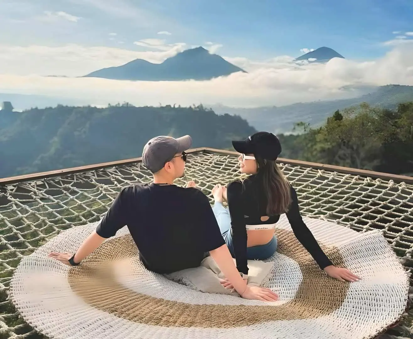 情侶在Akasa Kintamani咖啡館網床上，遠眺峇里島巴杜爾山與周圍壯麗火山景觀。