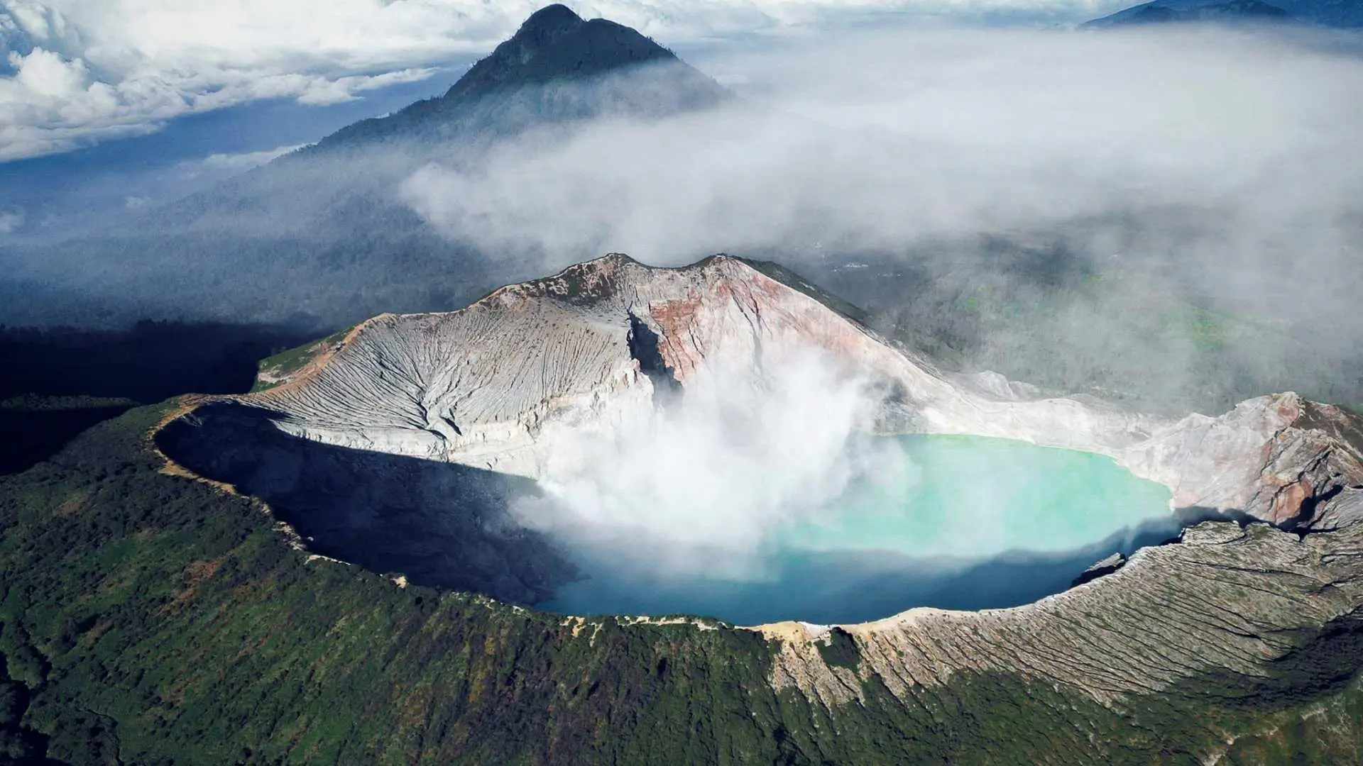 バリ島発イジェン火山日帰りツアー。エメラルドグリーンの火口湖と周囲の火山地形を俯瞰する壮大な空撮。