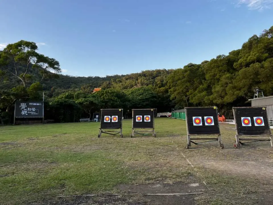 Taipei Xihu Archery Range's spacious outdoor field features multiple targets for archery experiences, surrounded by distant green mountains, offering picturesque views and an ideal setting for All-Star Sports Day training.