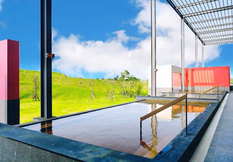 สระน้ำพุร้อนกลางแจ้งของ South Garden Hotels & Resorts Taoyuan ล้อมรอบด้วยท้องฟ้าสีครามและเนินเขาสีเขียว มอบประสบการณ์การแช่น้ำร้อนที่ผ่อนคลายห่างไกลจากความวุ่นวายของเมือง