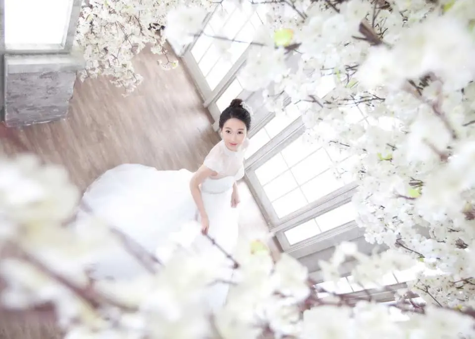 韓國吉安得婚紗攝影，新娘穿著優雅白紗，在繁花錦簇的室內景觀中由上往下拍攝，獨特的視角展現新娘甜美笑容。
