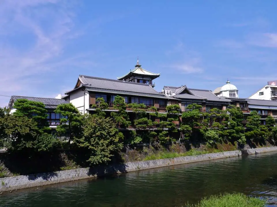 伊東市内の川沿いに建つ伝統的な日本建築。古風な瓦屋根と優雅な緑の木々が水面に映り、静岡独特の風情を醸し出し、東海バス2日券で便利に探索。