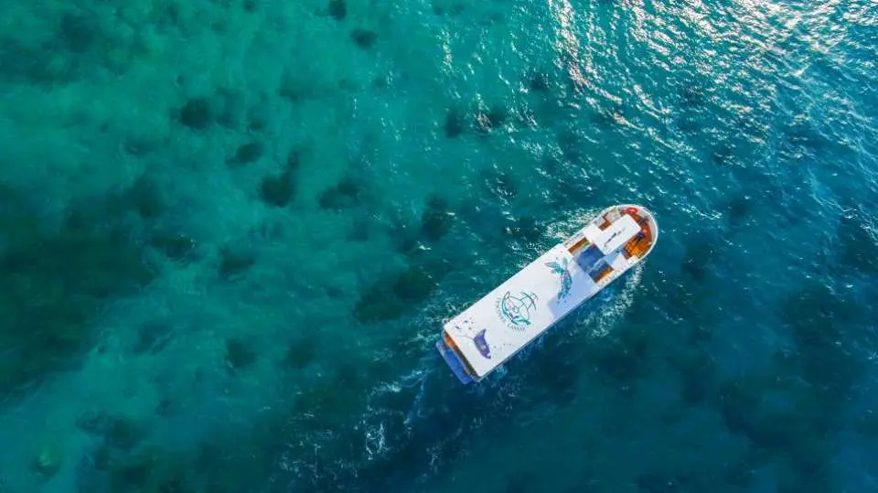 Aerial full view of the Xiaoliuqiu semi-submarine glass boat cruising on crystal-clear turquoise waters, with vibrant coral reefs and marine life visible below.
