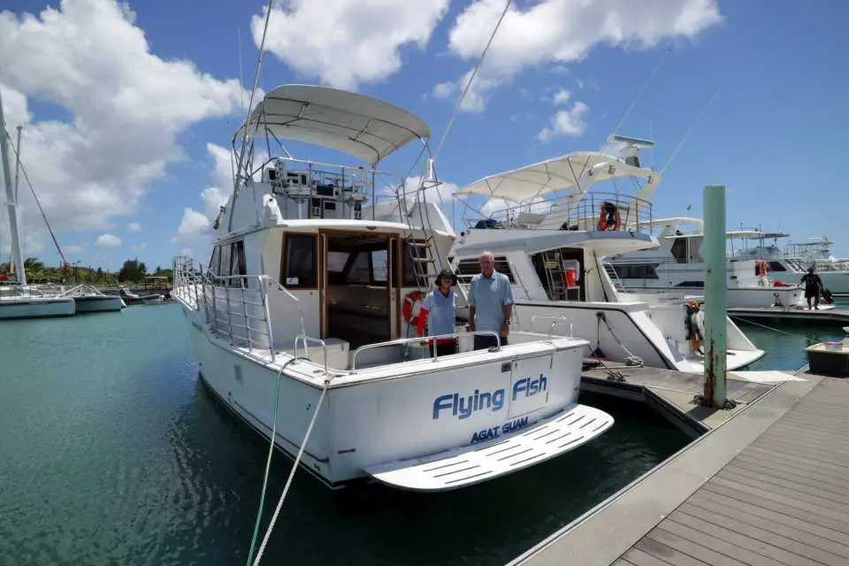 グアムの桟橋に停泊する白いヨット「Flying Fish」。フィッシュアイマリンパークのイルカウォッチング半日ツアーで、観光客を乗せて出発準備。