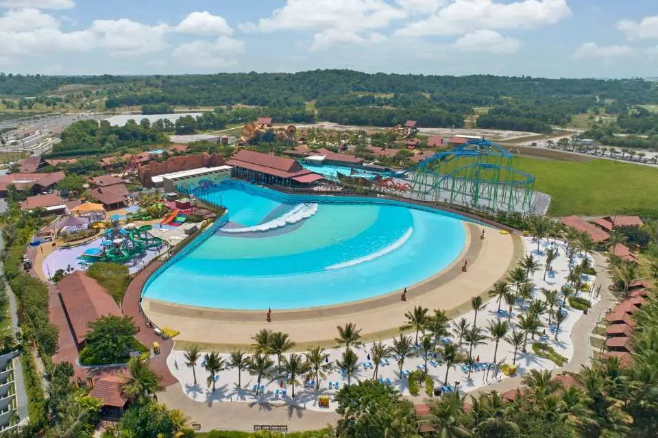 An impressive aerial view of Desaru Coast Adventure Waterpark, showcasing its vast wave pool, numerous water slides, and the sprawling layout amidst lush green landscapes.