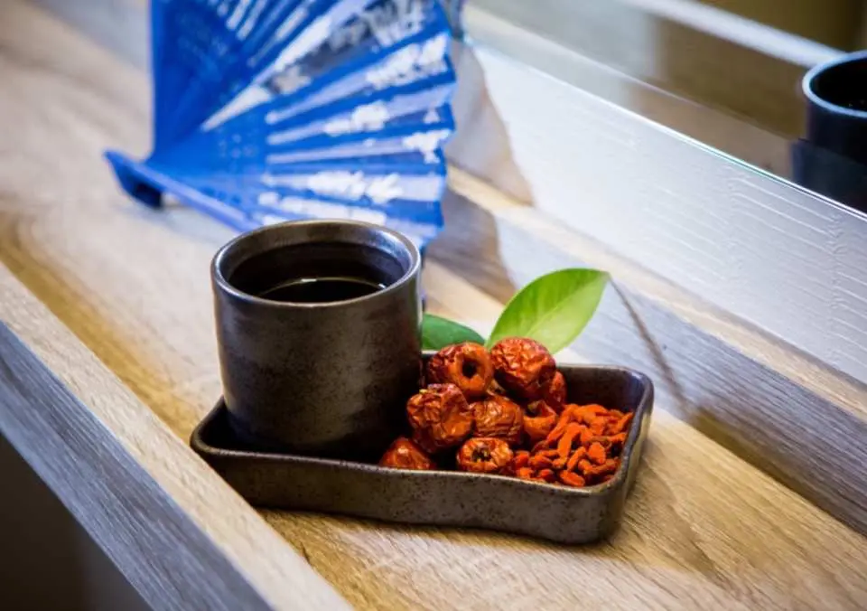 Complimentary traditional Chinese herbal tea with red dates and goji berries offered at Taipei's Xuanwu Wellness Center, warming guests after their massage for a complete wellness experience.