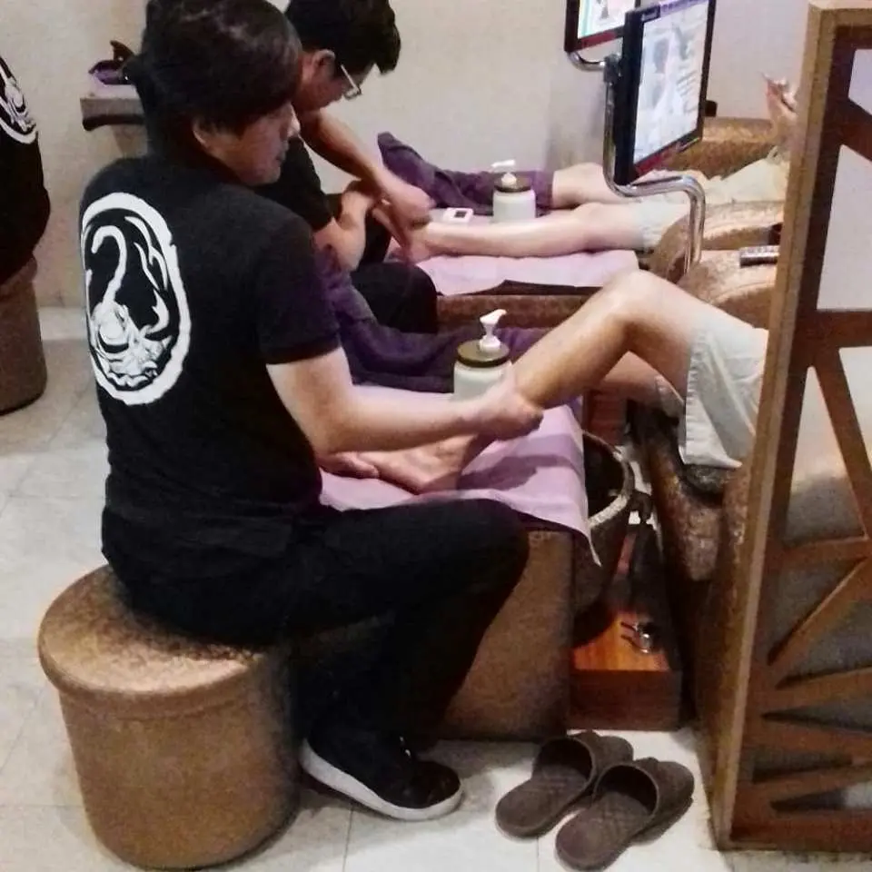 A professional therapist at Taipei's Xuanwu Wellness Center performing a soothing foot massage on a guest, expertly relieving foot fatigue.