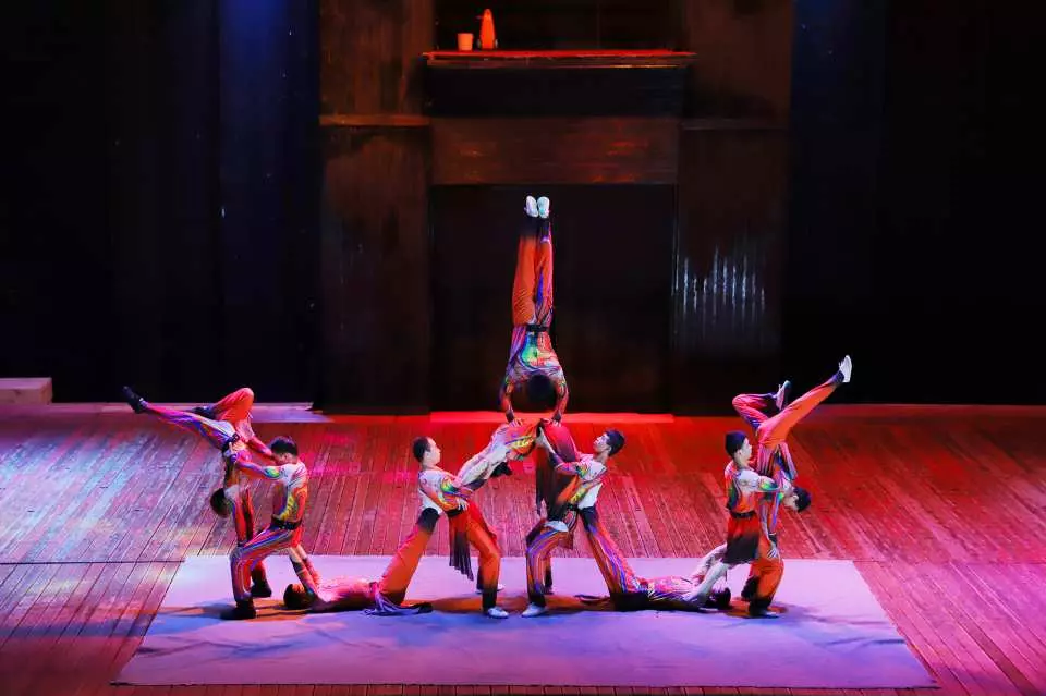 Jeju Island Sky Water Show's circus acrobatics, where multiple performers form spectacular human bridges and pyramids under red lighting, demonstrating masterful teamwork skills.