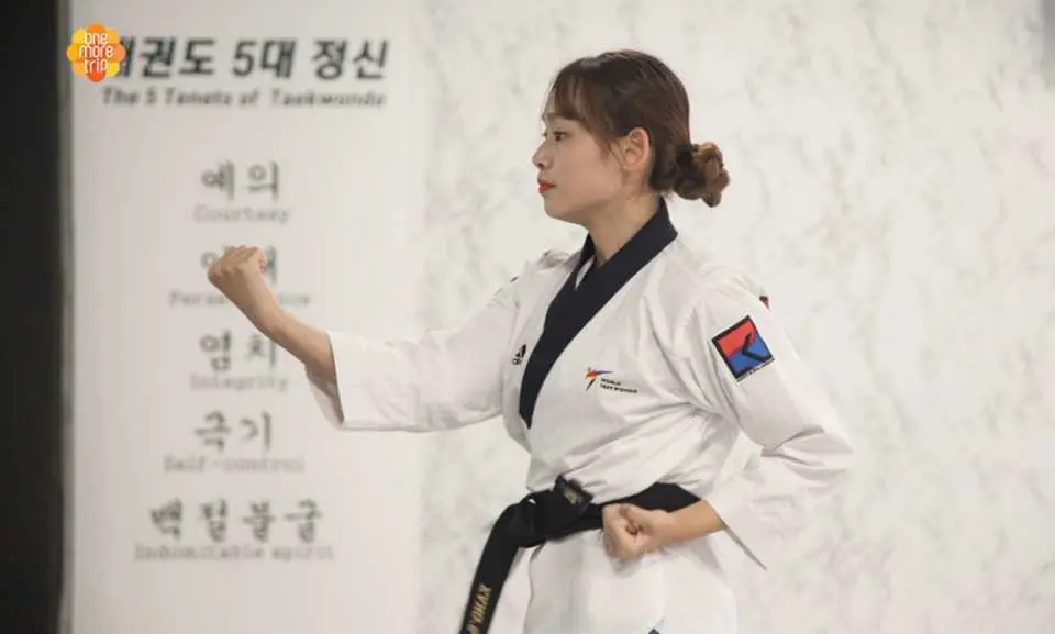 一位女性跆拳道教練穿著黑帶道服，示範精準的防禦或拳擊姿勢，在KANG'S跆拳道教授基本技能。