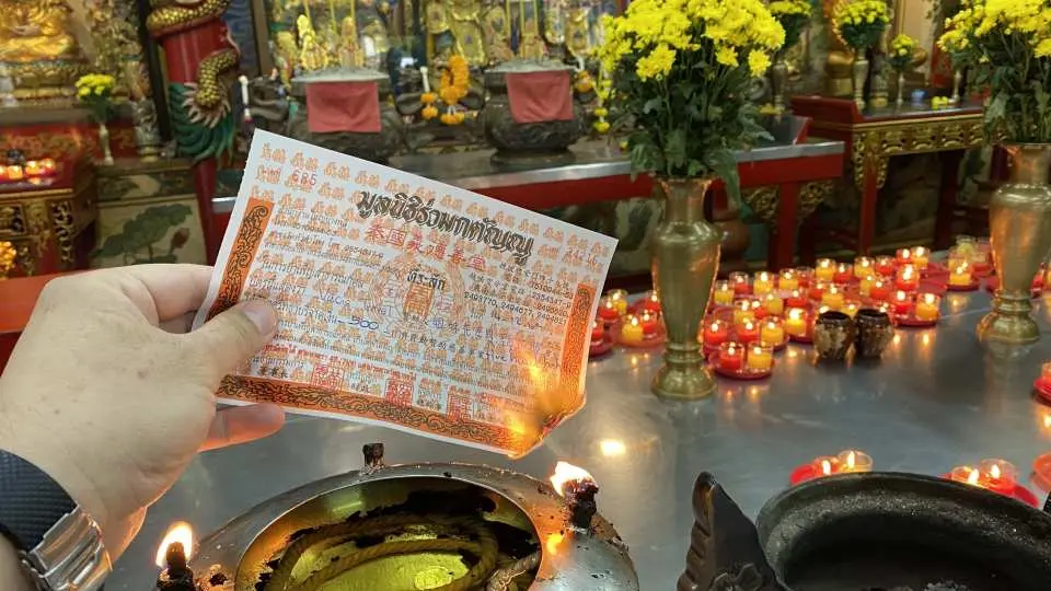 Following Thai custom, a merit slip with the donor's name for coffin donation is burned in a brazier at Bangkok's Ruamkatanyu Foundation, symbolizing a complete report to the deities.