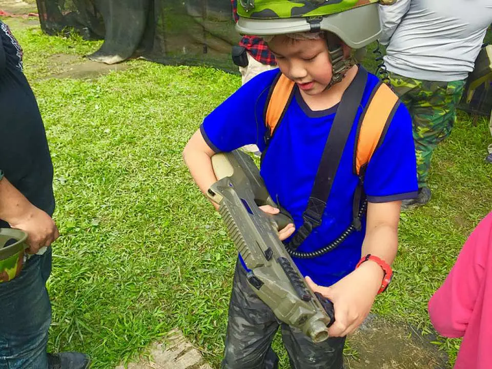 特寫一名戴著迷彩頭盔的孩童手持高科技鐳射槍，在台北準備參與一場無痛且安全的射擊體驗。