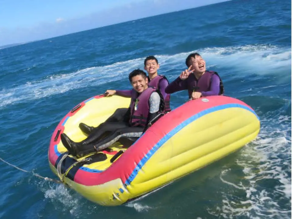 垦丁后壁湖刺激水上活动，三位游客乘坐曼波船被快艇拖曳，在海面上乘风破浪，享受摇摆刺激。