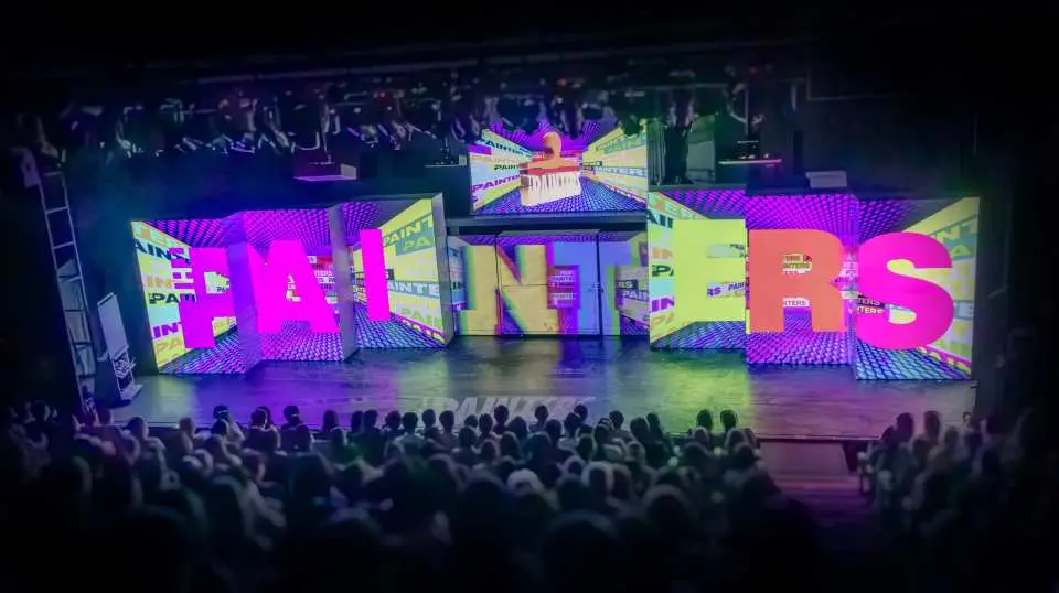 首爾塗鴉秀 Painters 劇場全景，觀眾席座無虛席，舞臺上充滿色彩的「PAINTERS」字樣配合3D投影。