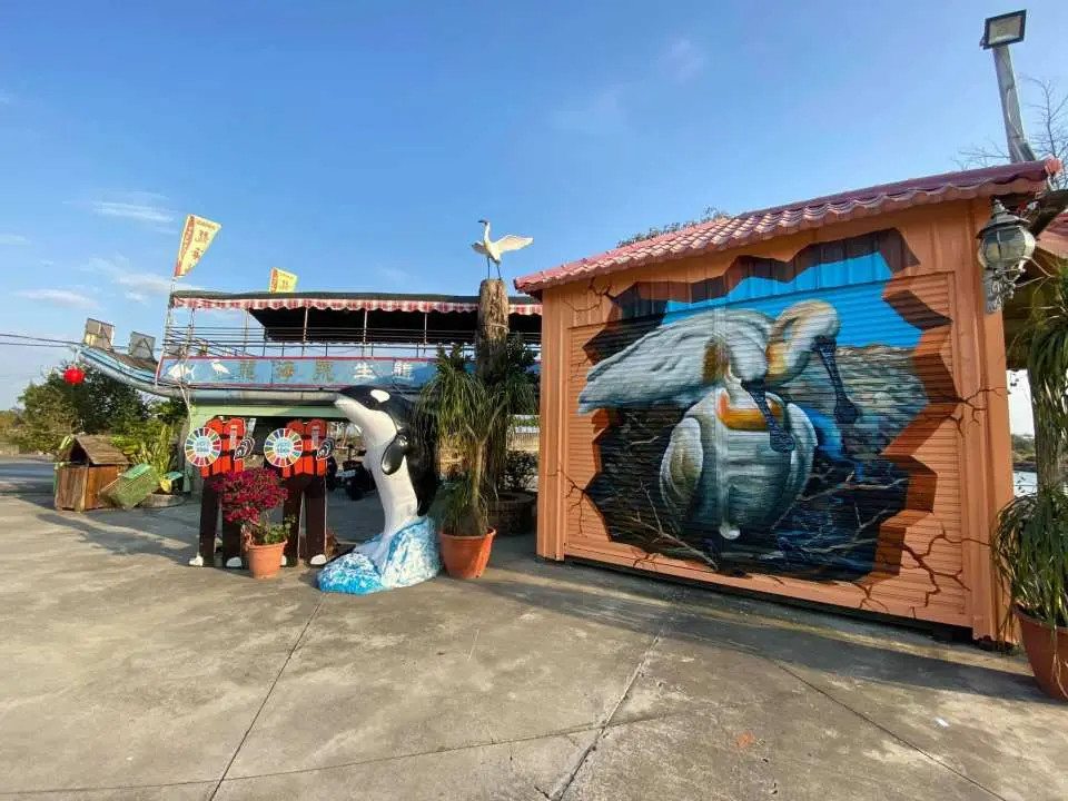 台南七股潟湖「龍海號」園區入口處，鯨魚雕塑與活潑的海洋主題彩繪牆，熱情迎接準備生態遊船及烤蚵的遊客。