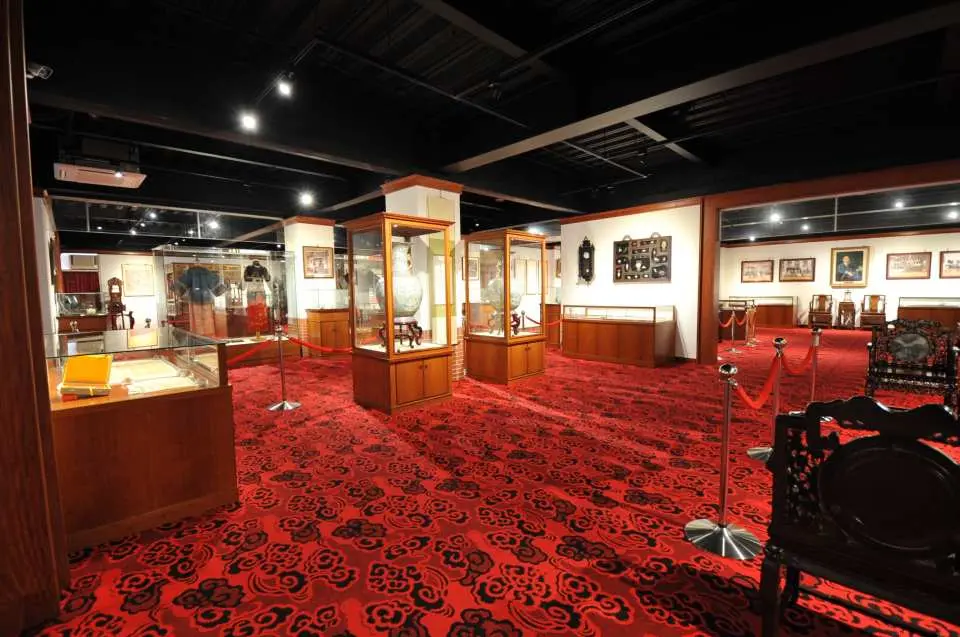 林獻堂博物館展覽廳，紅色地毯上設有多個玻璃展示櫃，陳列清代日治時期的古書圖、裝飾品與珍貴歷史文物。