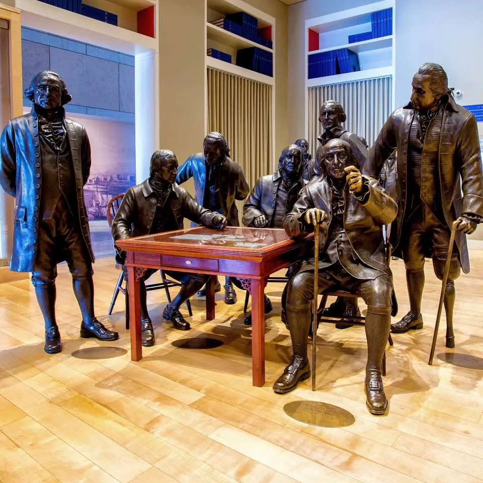 Bronze statues of America's Founding Fathers gathered around a table at the National Constitution Center, recreating a significant historical meeting and telling the nation's origin story.