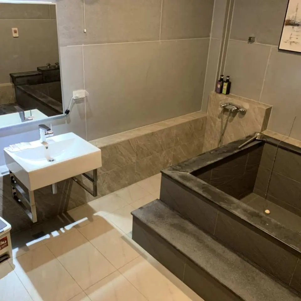 台南天喜悦温泉会馆的私人汤屋卫浴，可见具设计感的石砌浴池、简洁的白色洗手台与镜面，营造高品质且时尚的泡汤环境。