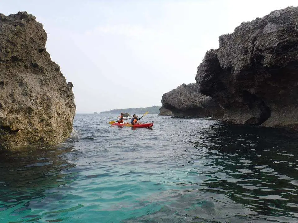 兩艘獨木舟在小琉球壯麗的沿岸海蝕洞與岩壁之間划行，探索獨特的海上秘境。