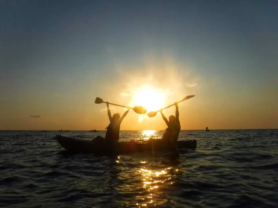 小琉球夕陽團獨木舟體驗，兩人划槳在金色餘暉中，剪影襯托出日落海上浪漫美景。