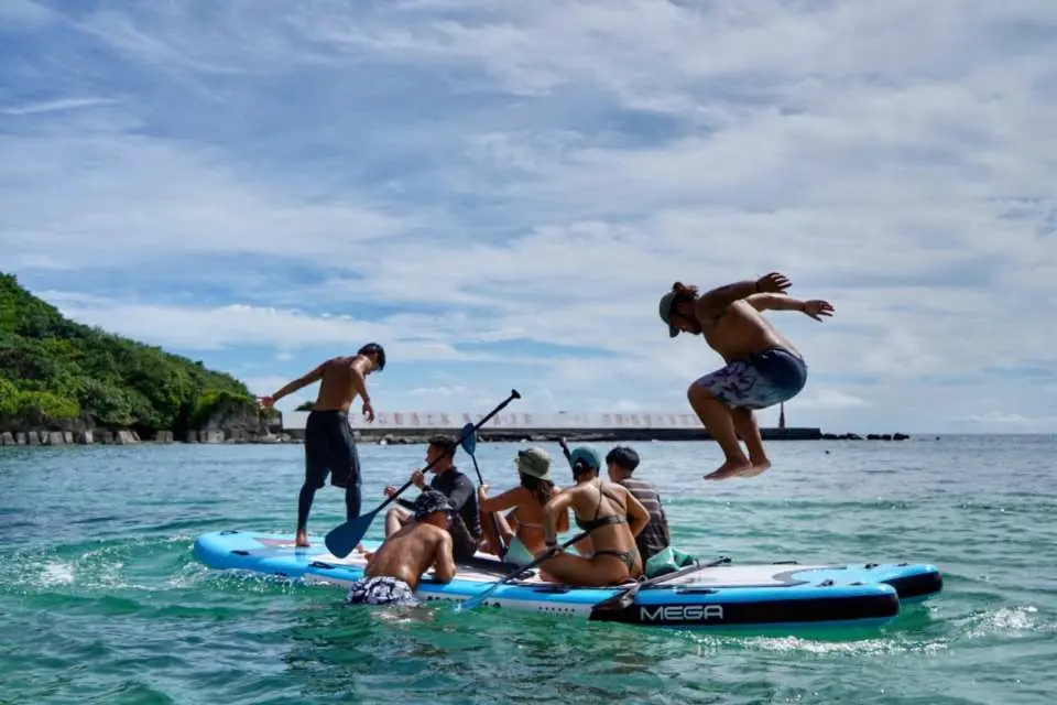 小琉球龍舟板SUP團體活動，一位男性興奮地從板上躍入海中，展現海上樂園的歡樂氛圍。
