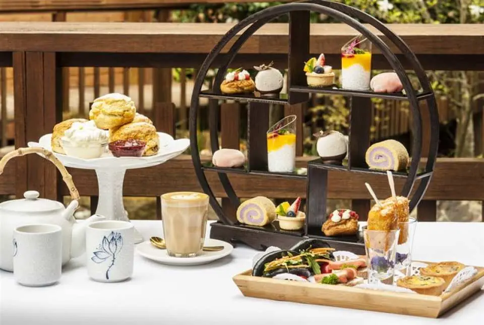 high tea round wooden 3-level carrying case filled with pastries with coffee and tea served
