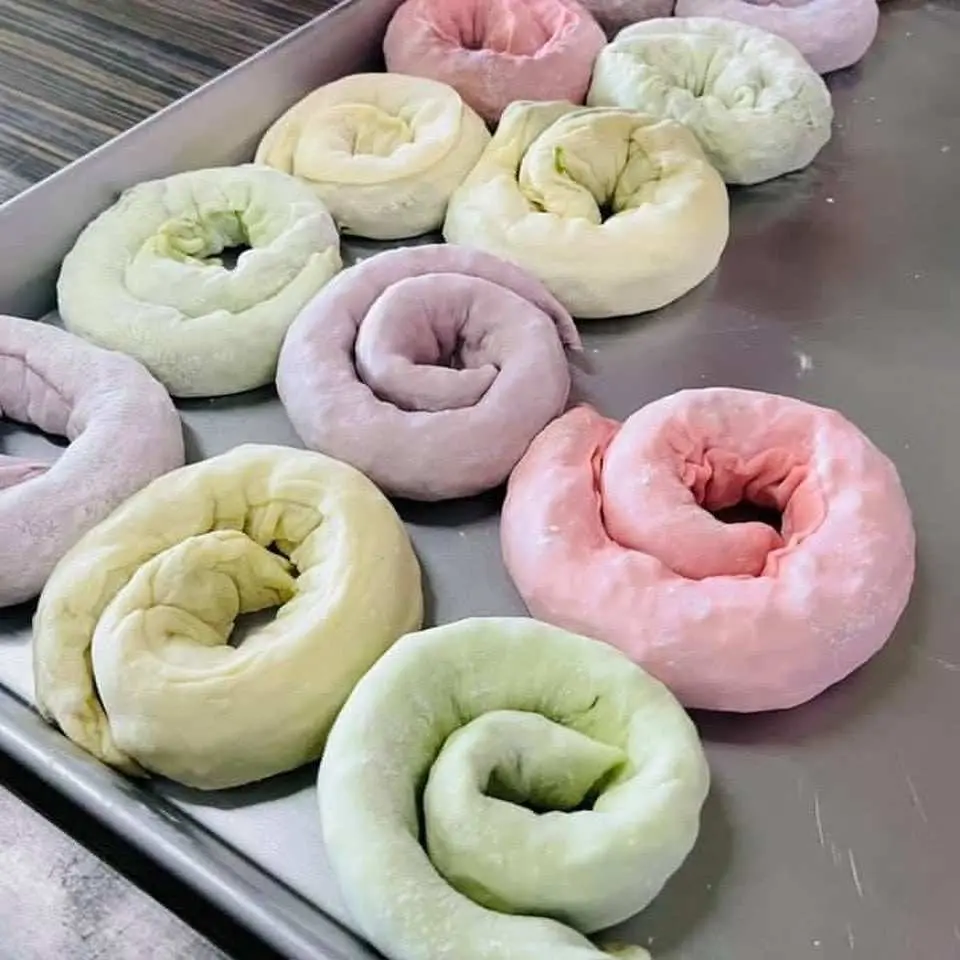 一盤準備製作的馬卡龍蔥多餅麵團，呈現粉、綠、黃等多種天然繽紛色彩，等待現做現煎。