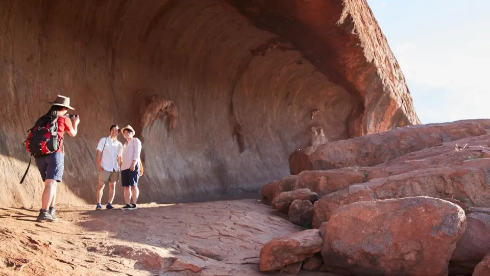 A guided group on the Uluru morning walk traces the sacred monolith's base, experiencing its massive scale and unique features in Australia's Northern Territory.
