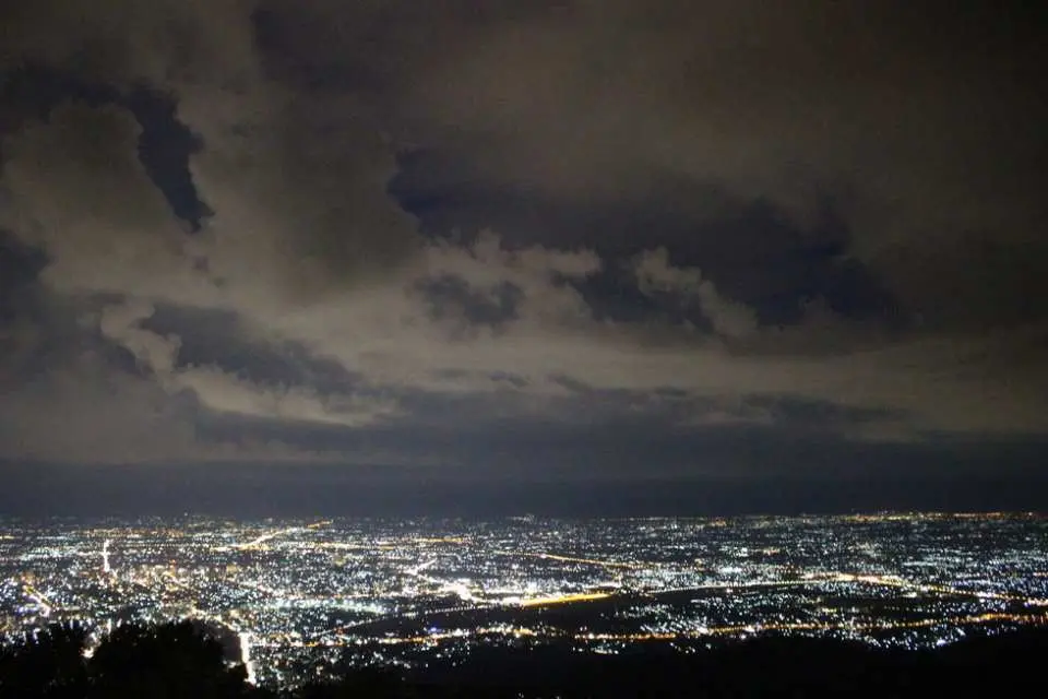 Magnificent night view of Chiang Mai city from Doi Suthep mountain top, with myriad city lights adorning the night, an unforgettable moment on a private tour experiencing Northern Thailand's urban landscape.