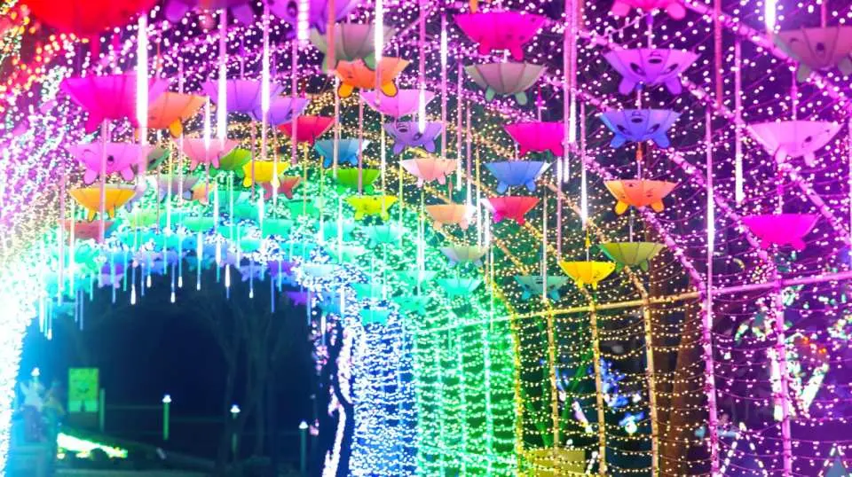 Stroll under a vibrant canopy of lights and umbrellas