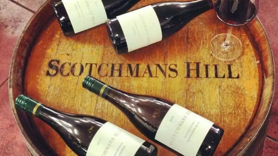 Scotchmans Hill winery's premium wine bottles and a glass displayed on a rustic wooden barrel, showcasing Bellarine Peninsula's finest selection from Victoria.