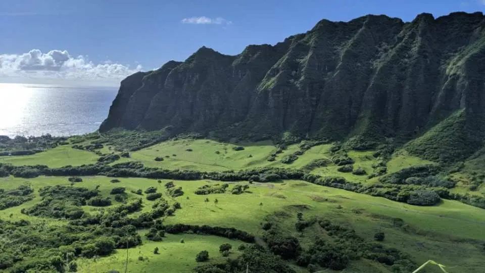 Panoramic view of Kualoa Ranch, Hawaii, showcasing vast green valleys, majestic mountains, and the beautiful blue Pacific coastline, perfect for tropical exploration.