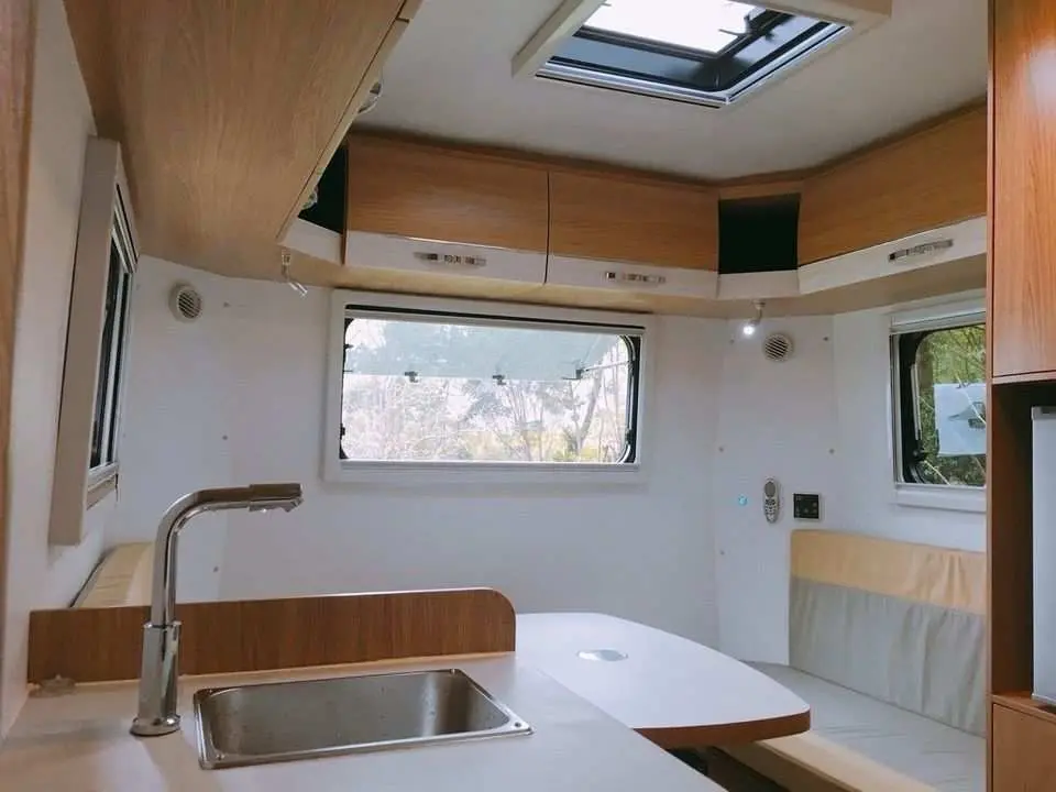 宜蘭溪河木露營車內部，設有功能齊全的小廚房和餐桌椅，提供舒適的車內生活空間，體驗移動式露營的便利。