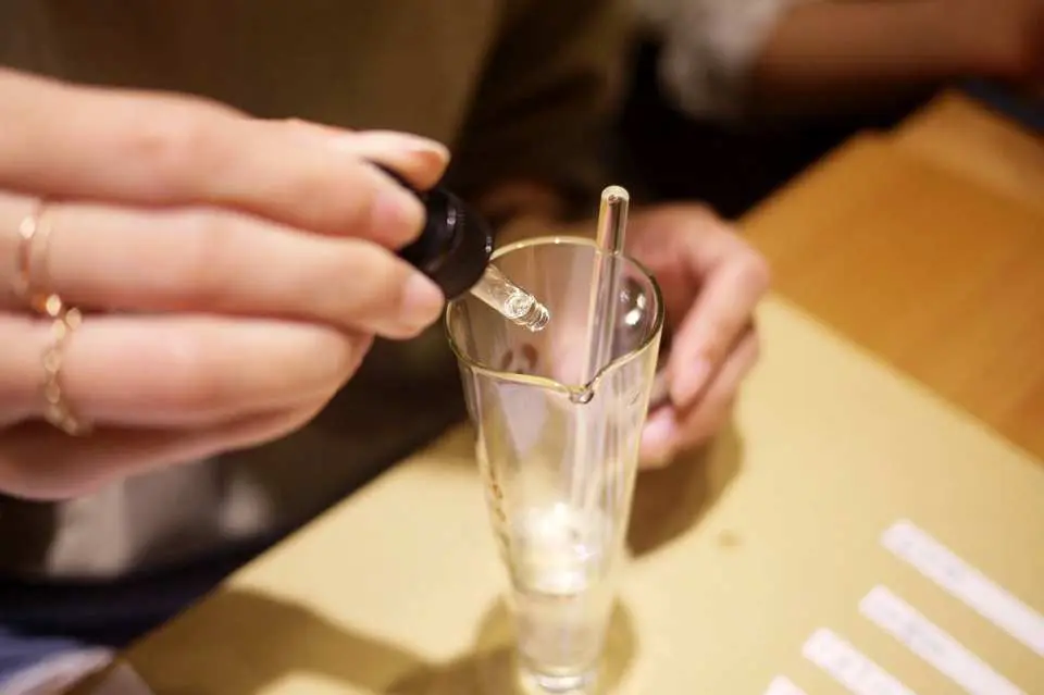 台北法式香水精油調香DIY體驗中，學員細心地將精油滴入量杯，精準調配每一滴香氣，享受創造的過程。