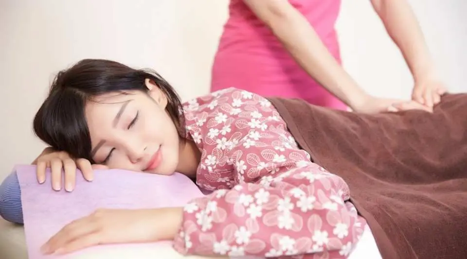 Inside Taipei's Manyiting Health Club, a customer in a floral robe enjoys a full-body massage, completely relaxing and falling asleep under the professional female therapist's care.