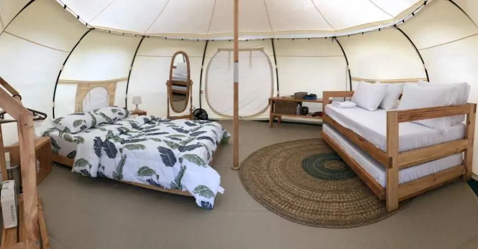 セブ島ナガの豪華キャンプテント内部の広々としたレイアウト。快適なダブルベッドと多機能な二段ベッドがあり、鏡と丸いラグも完備され、家族やグループでの宿泊に最適です。