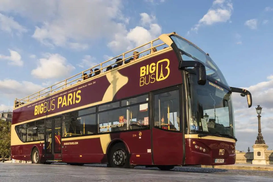 巴黎 Big Bus 隨上隨下雙層觀光巴士的完整外觀，車身印有品牌標誌，停靠於塞納河畔，讓旅客輕鬆探索巴黎著名景點。