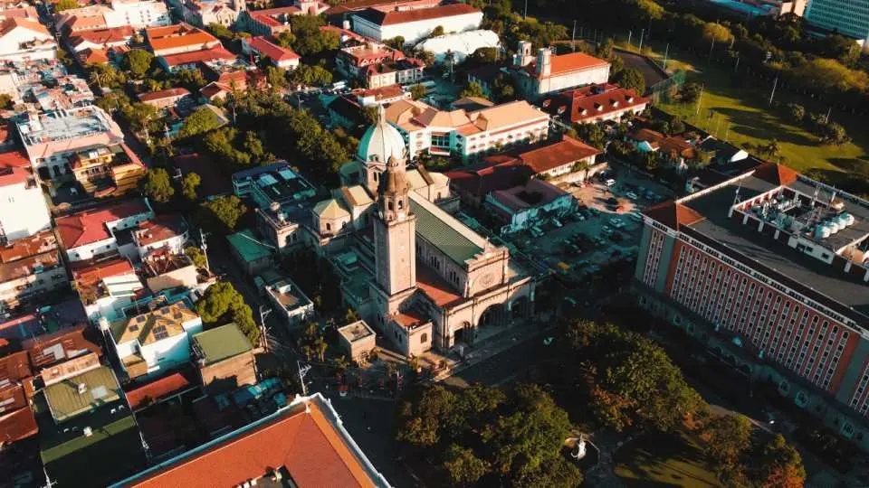 Aerial view of Manila city, featuring a grand historic church surrounded by urban buildings, blending the capital's modern charm with its deep history, an Intramuros day tour highlight.