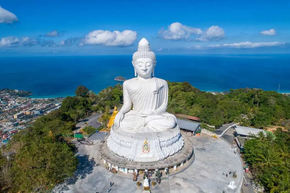 普吉岛大佛的宏伟白色大理石雕像，坐落在山顶，背后是普吉岛城镇与碧蓝安达曼海，阳光下佛像更显庄严，是体验普吉岛佛教文化和欣赏壮丽海景的绝佳地点。