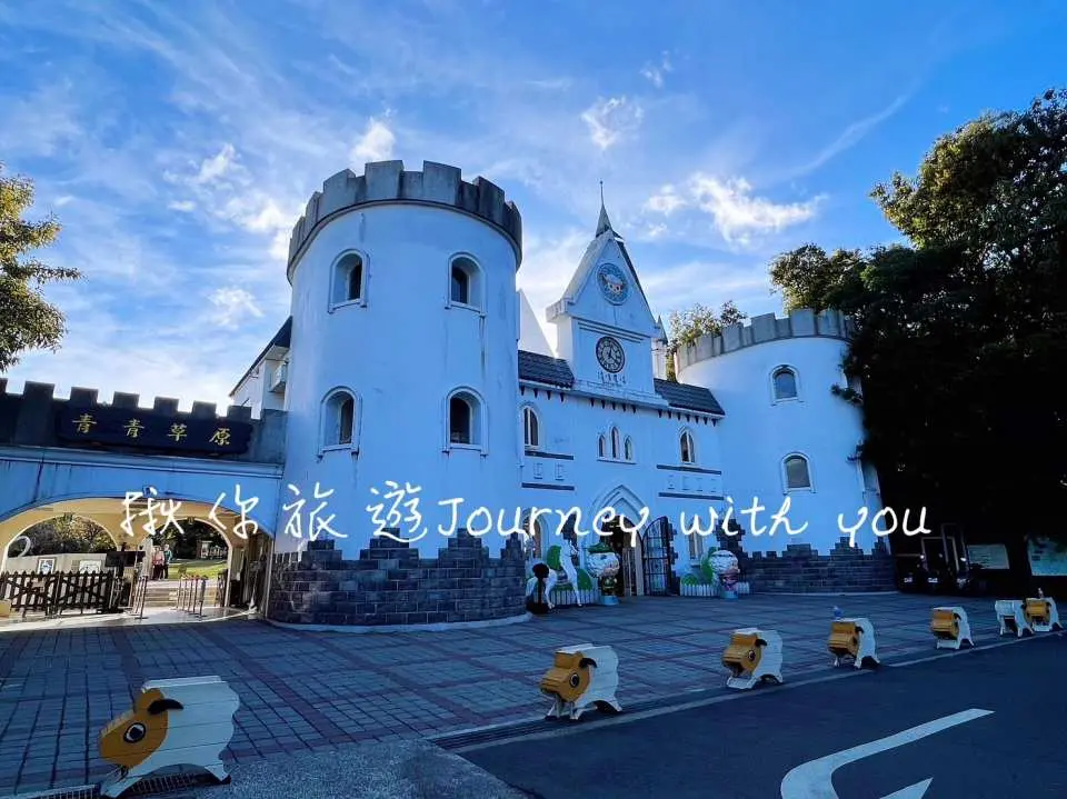 清境农场入口处的白色童话城堡建筑，尖塔与城墙充满欧式风格，地面绵羊造型装饰迎接游客，适合家庭拍照留念。